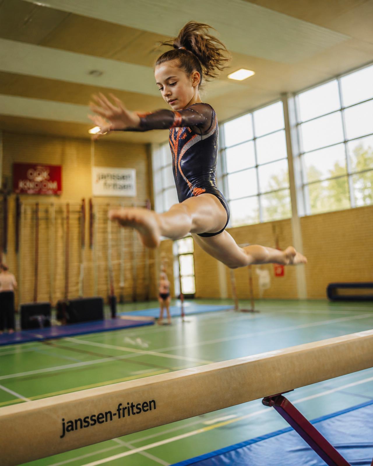 Turnster op de balk in de sportzaal van IJGV IJzevoorde